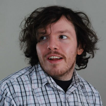 A brown hair, brown eyed man wearing a striped button down shirt